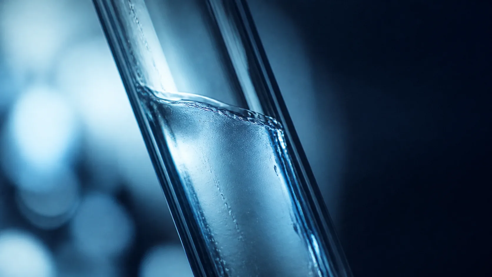 Inner surface of a smooth glass tube catching a thin film of clear liquid, extreme macro, backlit so the film glows