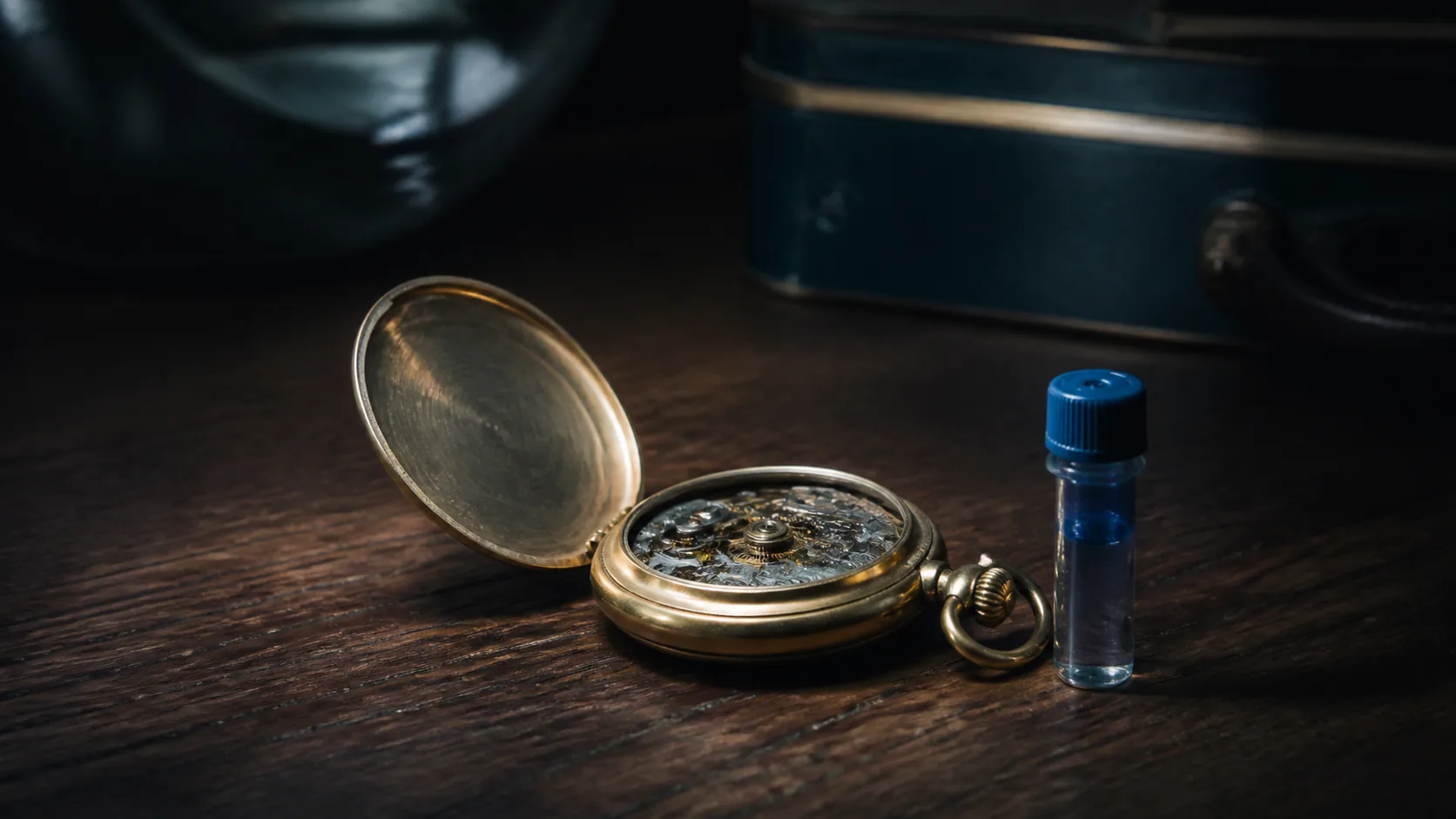 Open pocket watch face down beside a small cryovial on dark walnut, brass and glass