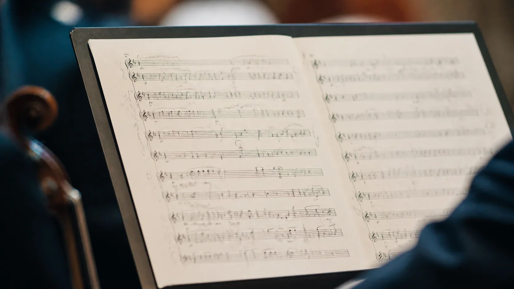 Sheet-music score on a stand with pencil annotations in the margins, the printed notes untouched, warm rehearsal-room light
