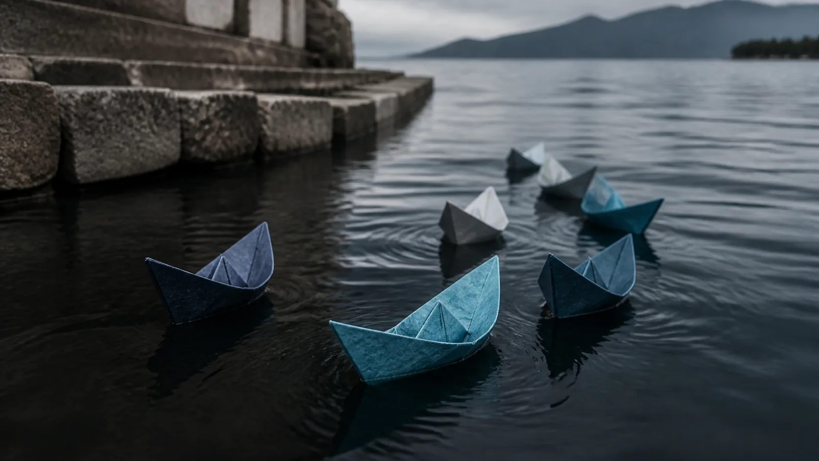 Small fleet of paper boats on still dark water, all pointing back toward a stone quay, overcast light