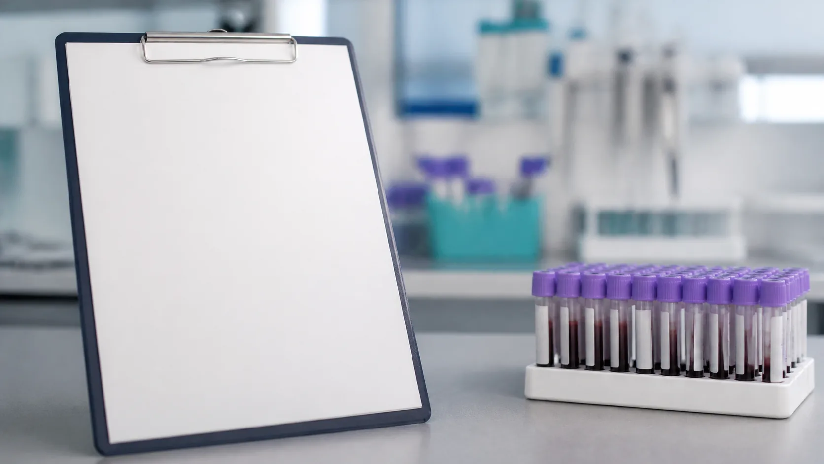 Laboratory bench with a printed blank paper form clipped to a board beside a rack of blood tubes, cold north light